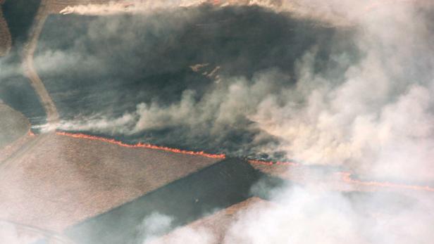 Ein Feldbrand erzeugt Rauchwolken über einem Feld.