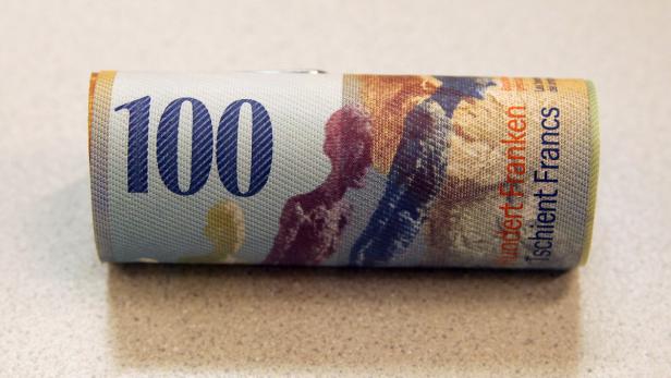 … Eine gerollte 100-Franken-Note liegt auf einem Tisch.