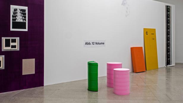 Eine Kunstinstallation mit bemalten Fässern und Tafeln in einem Ausstellungsraum.