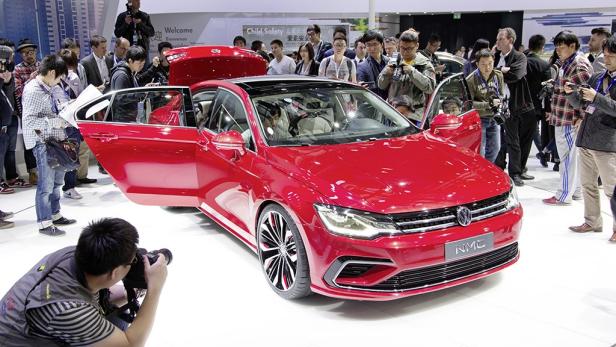 Ein roter VW NMC auf einer Automesse, umringt von Menschen.