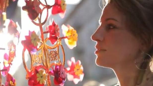 Eine Frau betrachtet einen chinesischen Glücksbringer mit bunten Blumen.