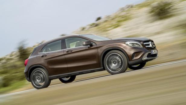 Ein brauner Mercedes-Benz GLA fährt auf einer kurvigen Straße.