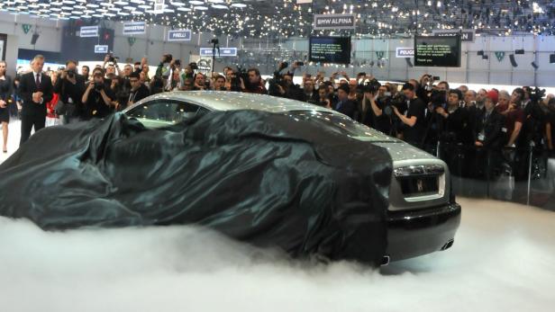 Ein Rolls-Royce wird auf einer Automesse unter einem Tuch enthüllt.