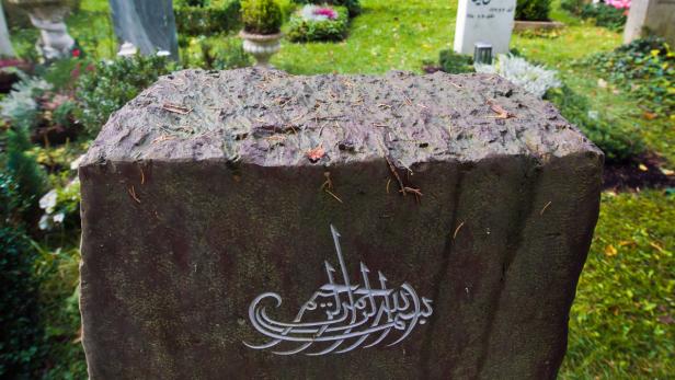 Ein Grabstein mit arabischer Kalligrafie auf einem Friedhof.