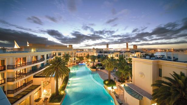 Blick auf ein luxuriöses Resort mit einem langen, gewundenen Pool bei Dämmerung.