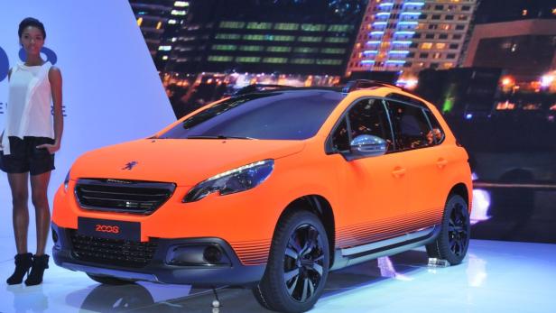 Ein orangefarbener Peugeot 2008 wird auf einer Bühne präsentiert.