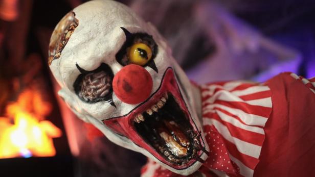 Eine gruselige Clown-Figur mit aufgerissenem Mund und einem roten Punkt als Nase.