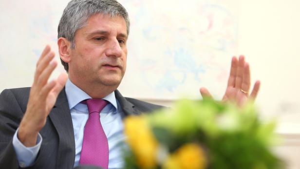 Ein Mann im Anzug gestikuliert während eines Gesprächs.