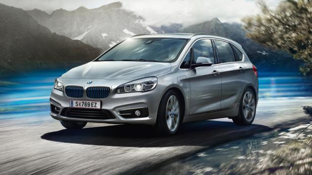 Ein silberner BMW 2er Active Tourer fährt auf einer Straße vor einer Bergkulisse.