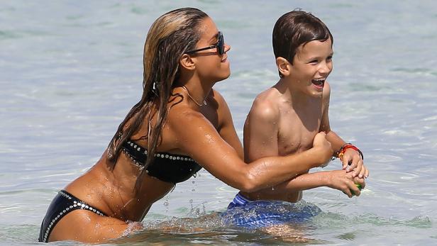 Eine Frau und ein Kind spielen lachend im flachen Wasser.