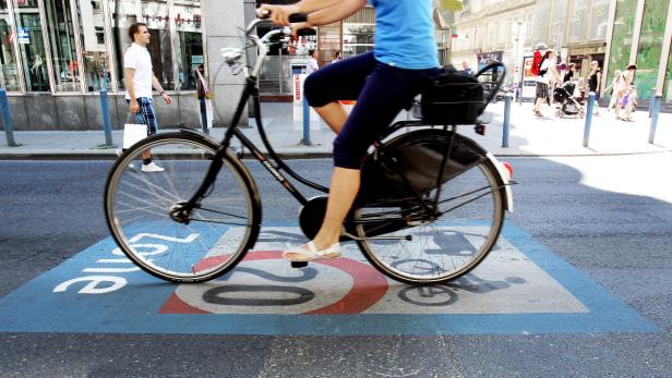 Eine Person fährt mit dem Fahrrad über eine blau markierte Zone in einer Stadt.