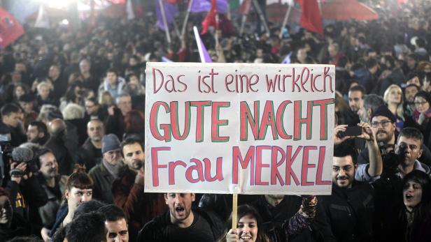 Eine Menschenmenge demonstriert mit einem Schild, auf dem steht: „Das ist eine wirklich GUTE NACHT Frau Merkel.“