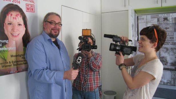 Hinterm Mikrofon, vor der Kamera: Erwin Schmitzberger mit Festivalplakat und Okto-TV-Team