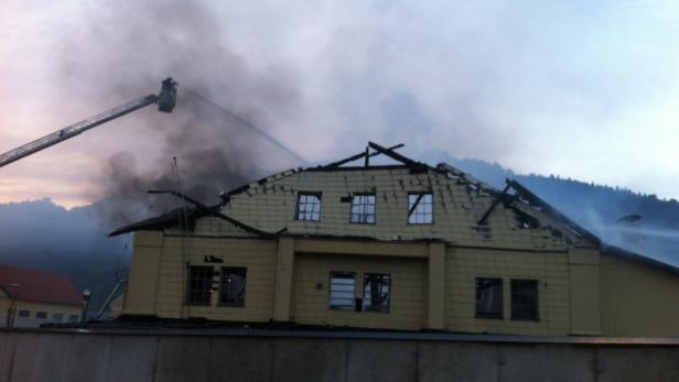 Ein gelbes Gebäude steht in Flammen, während die Feuerwehr versucht, den Brand zu löschen.