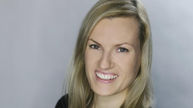 Porträt einer lächelnden Frau mit blonden Haaren.
