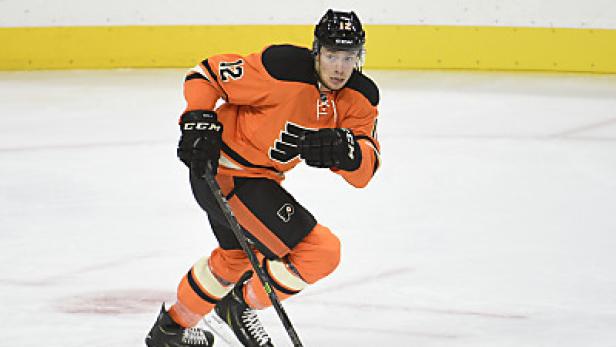 Ein Eishockeyspieler in orangefarbener Spielkleidung mit der Nummer 12 auf dem Eis.