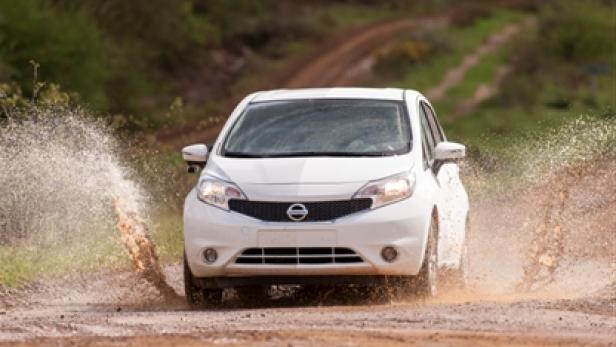 Ein weißer Nissan Note fährt durch eine schlammige Wasserpfütze.