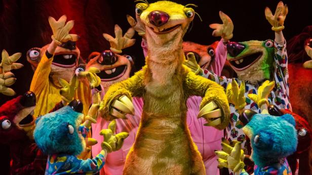 Sid, das Faultier, und andere Charaktere aus „Ice Age“ treten auf einer Bühne auf.