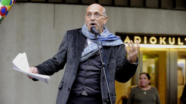 Ein Mann mit Schal spricht am Mikrofon vor dem Schriftzug „Radiokult“.