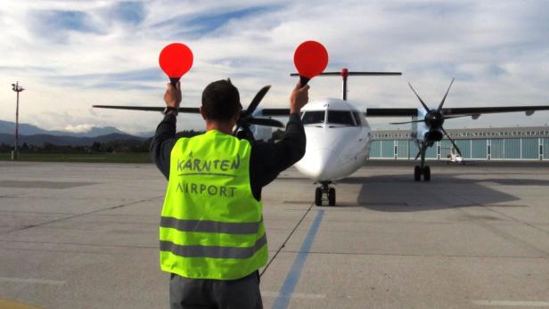 Ein Flugzeug wird von einem Mitarbeiter des Kärnten Airport eingewiesen.