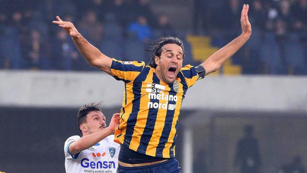 Ein Fußballspieler jubelt mit erhobenen Armen auf dem Spielfeld.