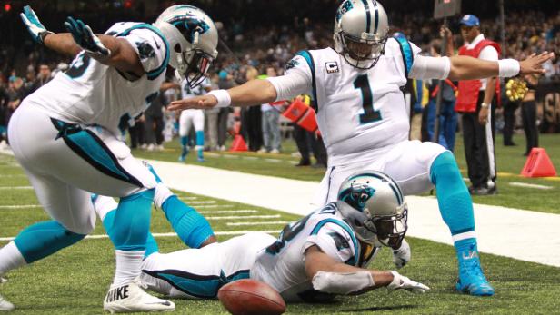 Ein Footballspieler wird getackelt, während andere Spieler um ihn herum stehen.