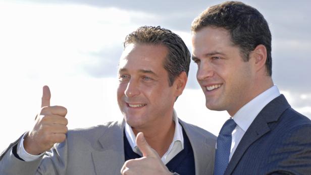 Zwei Männer im Anzug lächeln und zeigen den Daumen nach oben.