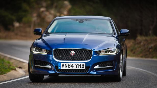 Ein blauer Jaguar XE fährt auf einer kurvenreichen Straße.