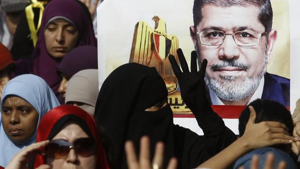 Frauen protestieren vor einem Porträt von Mohammed Mursi.