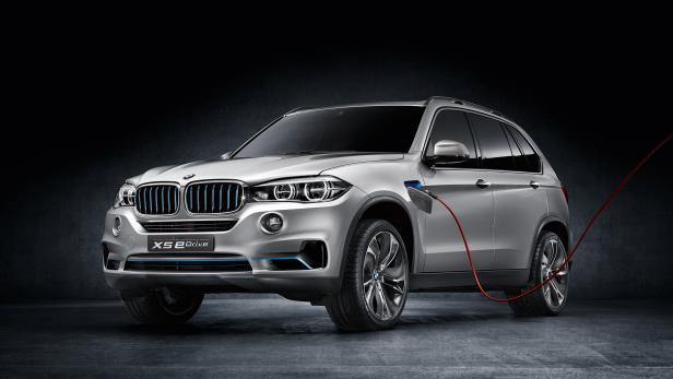 Ein silberner BMW X5 eDrive wird mit einem roten Kabel aufgeladen.