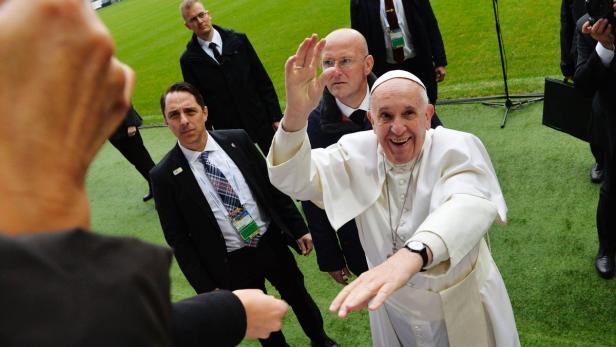 Papst Franziskus winkt lächelnd in die Kamera.