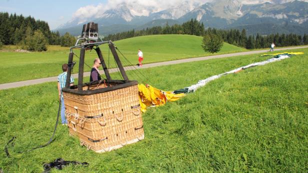 APA14255942-2 - 22082013 - OBERNDORF - ÖSTERREICH: ZU APA 0189 CI - Der Heißluftballon von dem ein Mann am Donnerstag, 22. August 2013, in Oberndorf im Tiroler Bezirk Kitzbühel in den Tod stürzte. Der Mitarbeiter der Heißluftballonfirma hatte Fahrgästen beim Aussteigen geholfen und als sich das Gefährt plötzlich wieder nach oben bewegte, hielt sich der Mann am Korb fest, ehe ihn schließlich die Kräfte verließen und er rund 100 Meter in den Tod stürzte. APA-FOTO: ZEITUNGSFOTO.AT