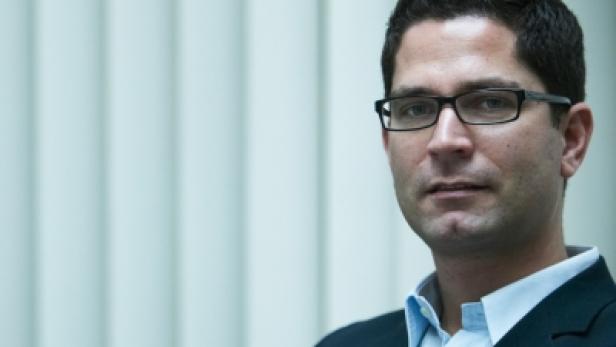 Ein Mann mit Brille, Hemd und Sakko blickt in die Kamera.