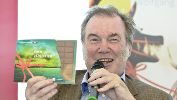 Ein Mann präsentiert eine Tafel „Wien Zartbitter“-Schokolade in einem Mikrofon.