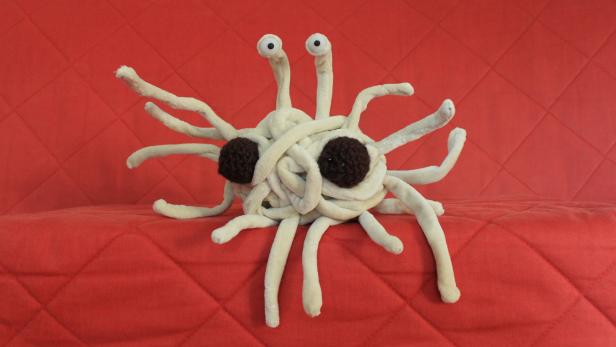 Ein Plüschtier des Fliegenden Spaghettimonsters auf einem roten Untergrund.