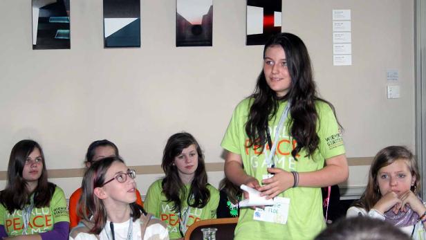 Eine junge Frau präsentiert vor einer Gruppe Jugendlicher ein Projekt zum Thema Frieden.