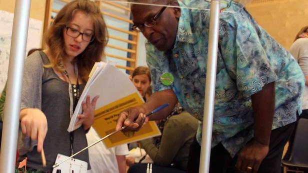 Eine Frau und ein Mann betrachten ein Modell einer Kriegslandschaft mit Figuren und Flugzeugen.