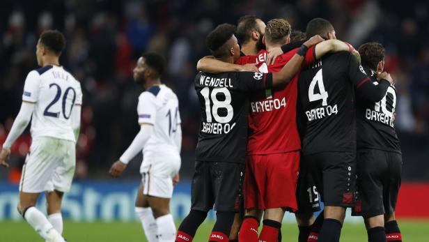 Fußballspieler von Bayer 04 Leverkusen umarmen sich auf dem Spielfeld.