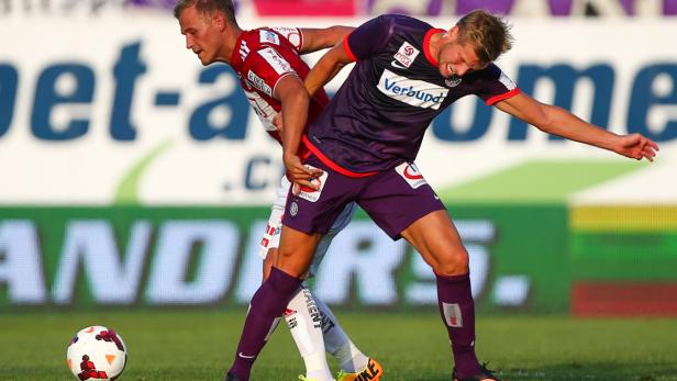 Zwei Fußballspieler kämpfen um den Ball während eines Spiels.