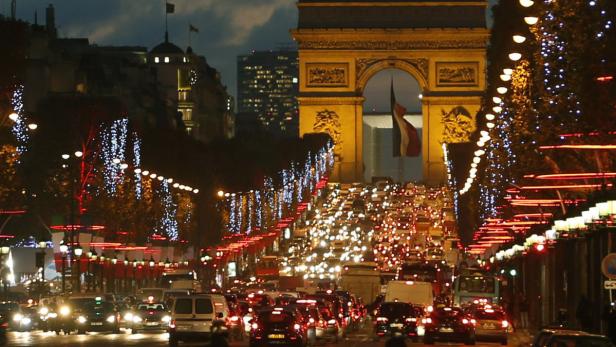 Christmas holiday lights hang from trees to illuminate the Champs Elysees as rush hour traffic fills the avenue leading up to the Arc de Triomphe in Paris November 22, 2012. REUTERS/Charles Platiau (FRANCE - Tags: CITYSPACE SOCIETY ENTERTAINMENT)