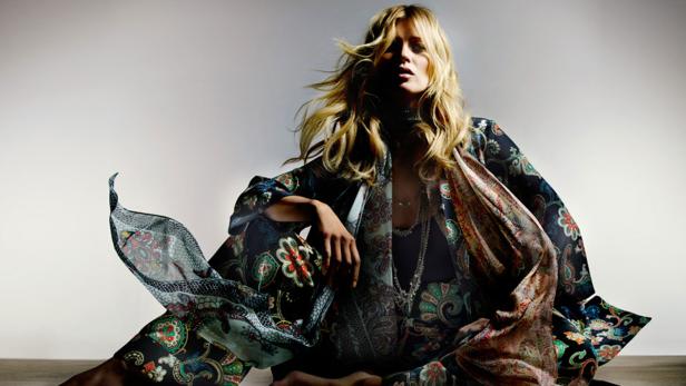 Eine Frau mit blonden Haaren sitzt in einem farbenfrohen, gemusterten Kimono.