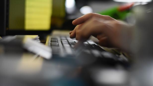 Eine Hand tippt auf einer schwarzen Computertastatur.