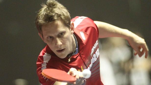 Ein Tischtennisspieler schlägt den Ball mit seinem Schläger.