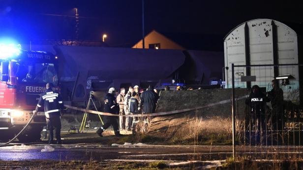 Einsatzkräfte von Feuerwehr und Polizei arbeiten an einem Tatort in der Nacht.