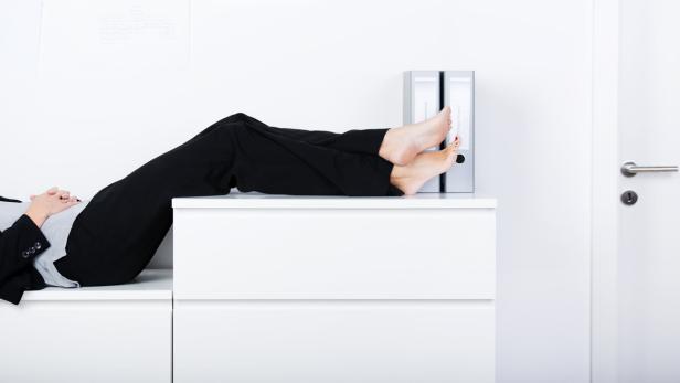 Eine Frau im Büro hat die Füße auf dem Schrank abgelegt.