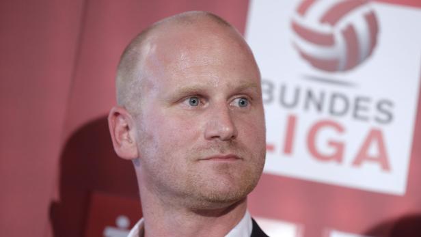 Ein Mann steht vor einem Logo der Volleyball Bundesliga.