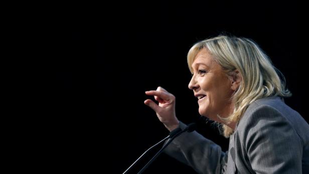 Marine Le Pen gestikuliert während einer Rede vor einem schwarzen Hintergrund.