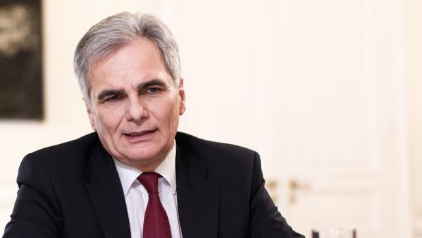 Ein Mann mit grauem Haar, Anzug und roter Krawatte blickt in die Ferne.