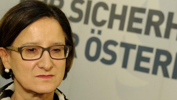 Nahaufnahme einer Frau mit Brille vor dem Schriftzug „Sicherheit Österreich“.