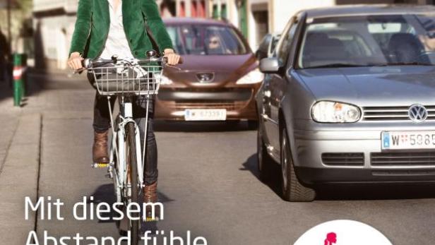 Eine Frau fährt mit dem Fahrrad auf einer Straße in Wien, flankiert von parkenden Autos.